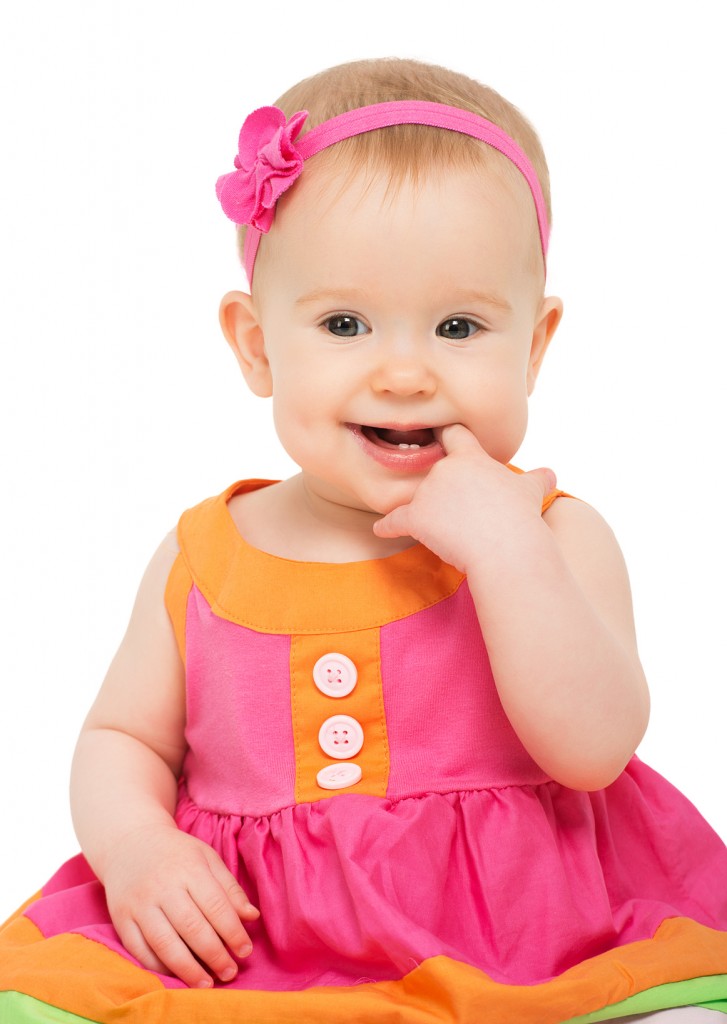happy little sly baby girl in bright multicolored festive dress isolated on a white background