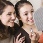 Smiling Mother and Daughter with Lipstick, Looking at Mirror